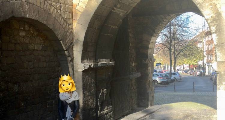 Personne modifiée avec un visage en emoji se tenant dans l'arche d'une porte de ville médiévale.