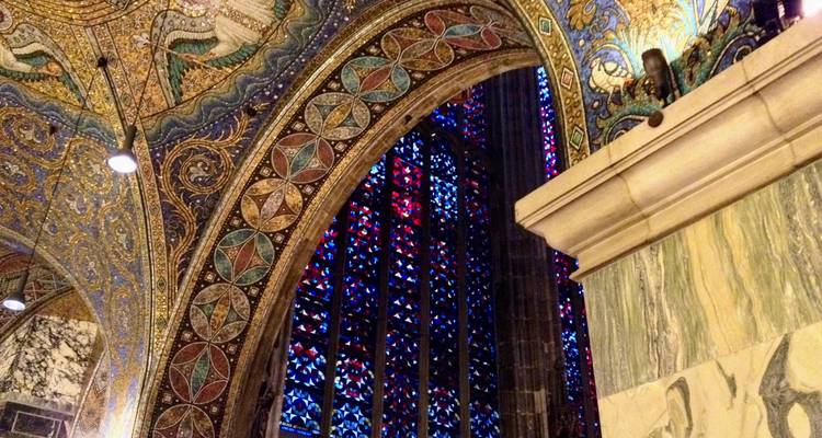 Porche recouvert de mosaïques avec des motifs en or détaillés à côté d'une vibrante fenêtre en vitrail.