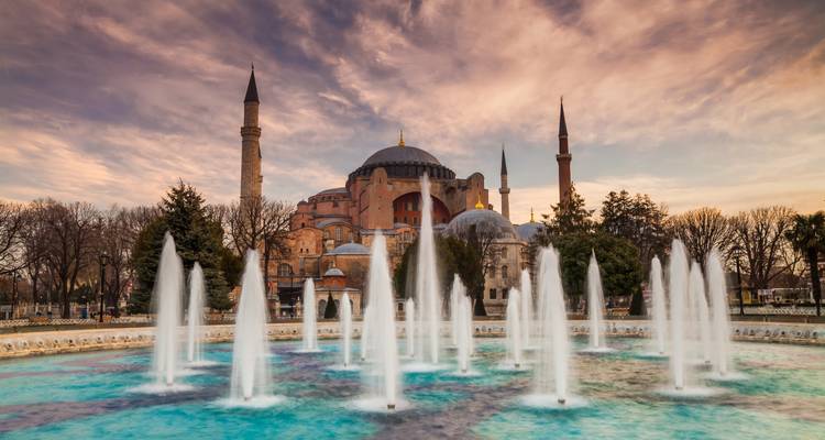 Evening view of Hagia Sophia behind illuminated fountains with a dramatic sky.
