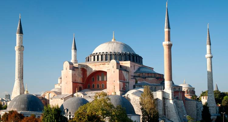 Clear daytime shot of Hagia Sophia's domes and minarets against a vivid blue sky.