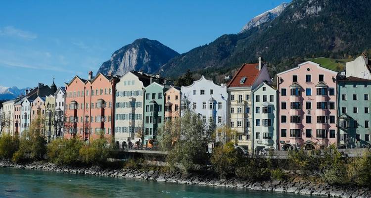 Rangée de maisons de ville de couleurs pastel le long de la rivière Inn turquoise avec les montagnes alpines se dressant derrière à Innsbruck.