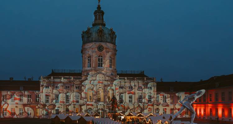 Palais baroque grandiose illuminé par des projections lumineuses artistiques lors d'un festival en soirée.