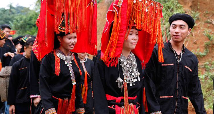 Junge Dorfbewohner in traditionellen schwarzen und roten ethnischen Kostümen bei einer Parade in einer Kulturveranstaltung.