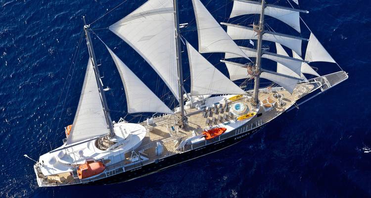 Vue aérienne d'un navire de luxe à quatre mâts naviguant sous toutes voiles dehors sur la mer bleu profond.
