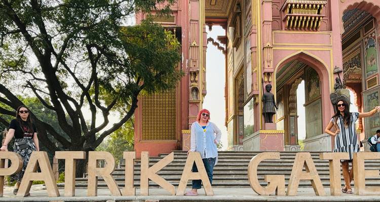 Les voyageurs se tiennent à côté des grandes lettres en bois de la Patrika Gate, un monument de Jaipur peint de couleurs éclatantes.