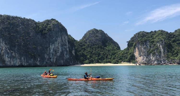 Los kayakistas reman a través de aguas esmeraldas rodeadas de formaciones de piedra caliza y acantilados de la jungla en la bahía de Lan Ha.