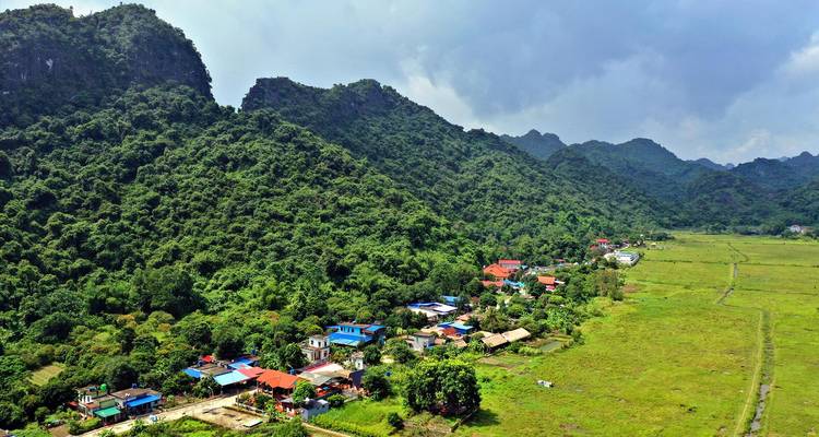 Vista aérea del pueblo de Viet Hai acurrucado entre las exuberantes montañas de piedra caliza y los campos de arroz abiertos.