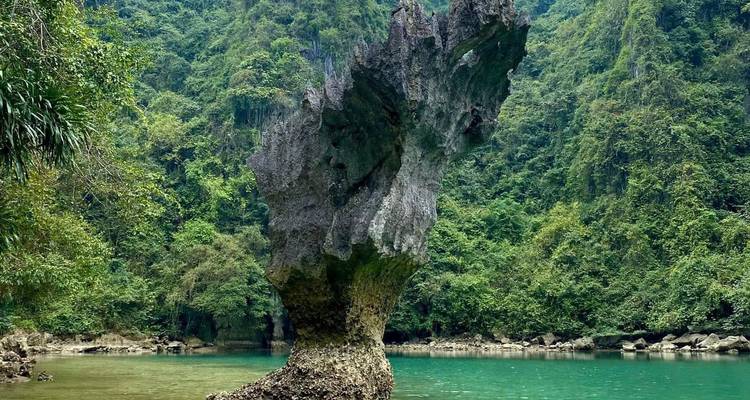 Un singular afloramiento de piedra caliza vertical que se eleva desde aguas de color verde jade en medio de la selva.