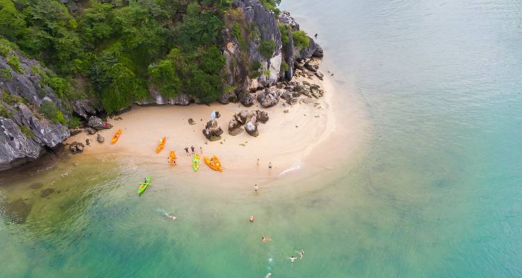 Vista aérea de una playa tropical diminuta con kayaks y nadadores en el agua verde esmeralda de la Bahía de Lan Ha