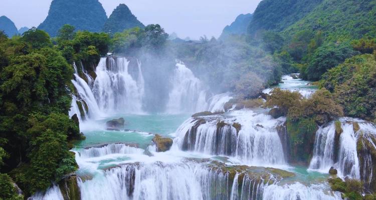 La majestuosa cascada de Ban Gioc en múltiples niveles cayendo a través del exuberante paisaje de karst verde.