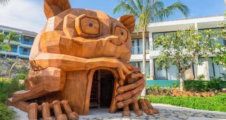 Grande structure en bois en forme de chat ressemblant à une maison de jeux installée dans un jardin de villégiature.