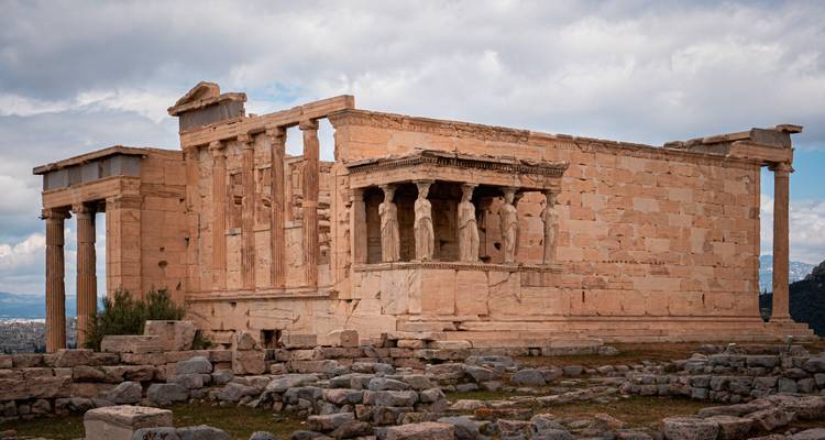 Der antike Erechtheion-Tempel mit seiner Karyatiden-Vorhalle steht auf der Akropolis unter einem dramatischen bewölkten Himmel.