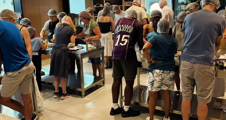 Les participants portant des filets à cheveux se rassemblent autour de tables en acier inoxydable dans un atelier de chocolat.