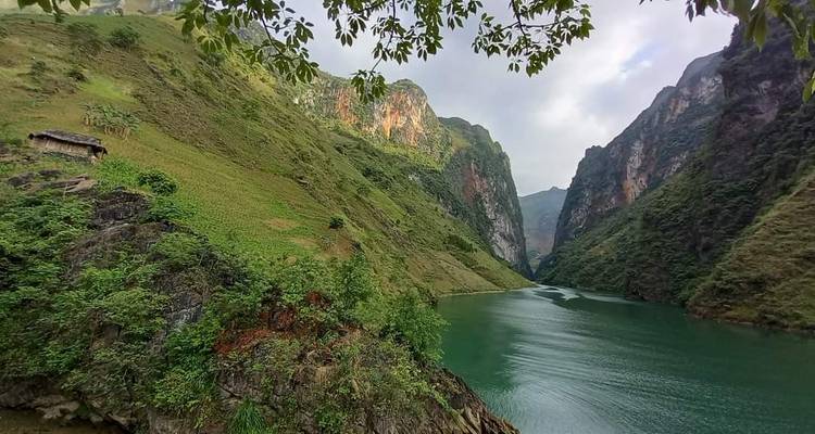 Lago tranquilo de cañón verde rodeado de colinas empinadas y exuberantes bajo un cielo nublado.