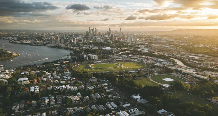 Vue aérienne de l'heure dorée de la ligne d'horizon de Brisbane et du fleuve avec le stade ovale au premier plan.