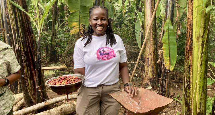 A smiling woman proudly displays a bowl filled with freshly picked coffee cherries in a plantation.