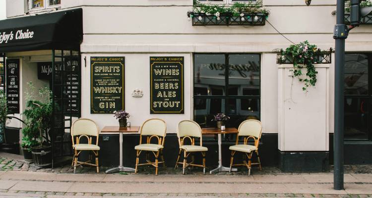 Charming Copenhagen street cafe with empty wicker chairs and vintage drink boards