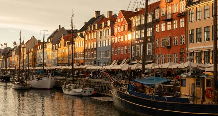 Golden evening light illuminates Nyhavn's colorful waterfront and docked sailing boats