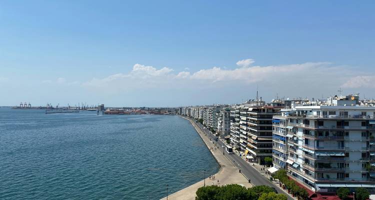 Une promenade côtière majestueuse de Thessalonique s'étend le long des eaux bleu vif de la mer Égée sous un ciel dégagé.