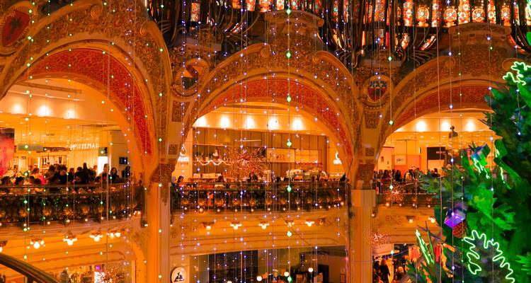 Arcade intérieure richement décorée avec des lumières étincelantes et un dôme en vitrail durant la période des fêtes.