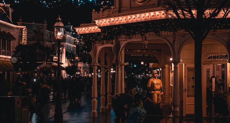 Des foules se promenant dans des galeries chaleureusement éclairées et des vitrines décorées de guirlandes lumineuses lors d'une soirée festive.