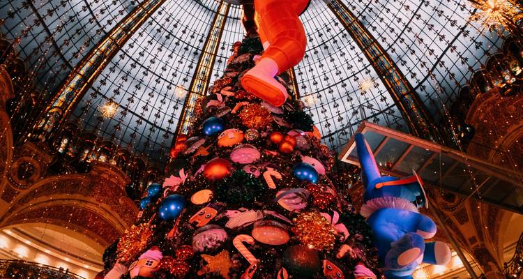 Vue ascendante d'un immense sapin de Noël coloré sous le dôme en verre orné d'un grand magasin.