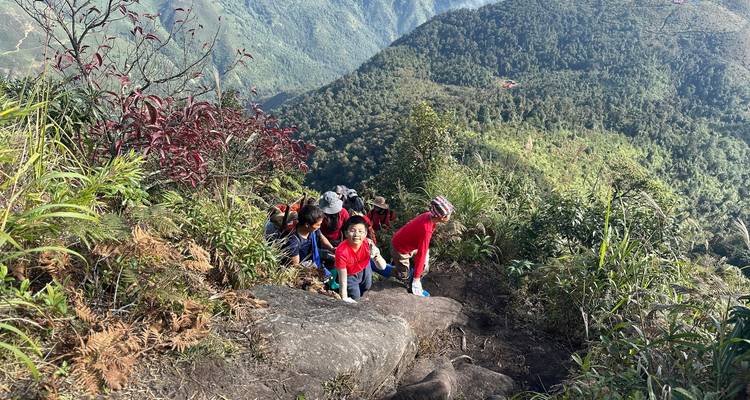 Les enfants grimpent avec enthousiasme une section rocheuse du sentier de montagne avec une vaste vallée verte en dessous