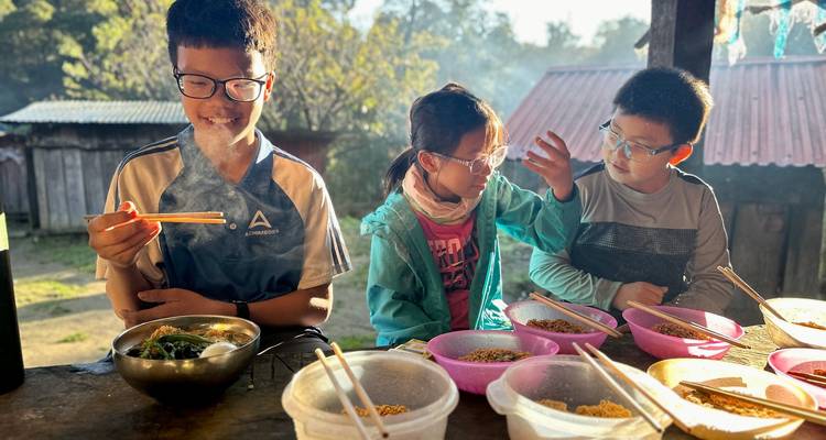 Les enfants dans une cuisine extérieure décontractée savourent des bols de nouilles fumants à la lumière de l'aube