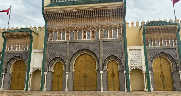 Grand portail triple avec des portes dorées ornementales et des carrelages de zellij au Palais Royal de Fès.