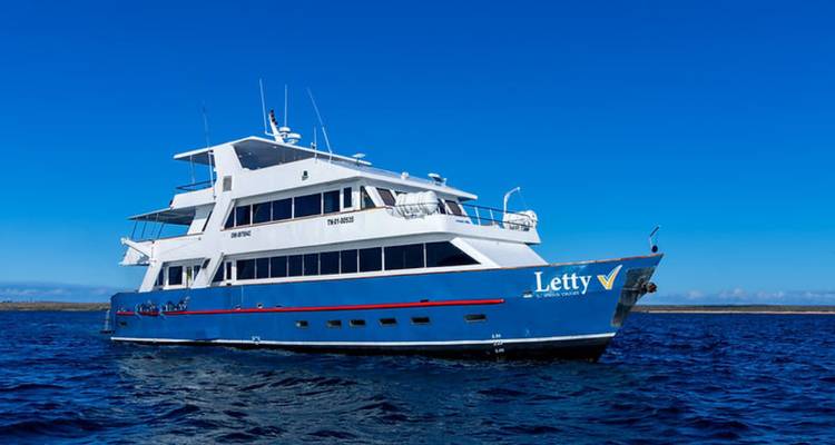 Yacht bleu de croisière habitable nommé Letty ancré dans les eaux calmes des Galápagos sous un ciel éclatant.