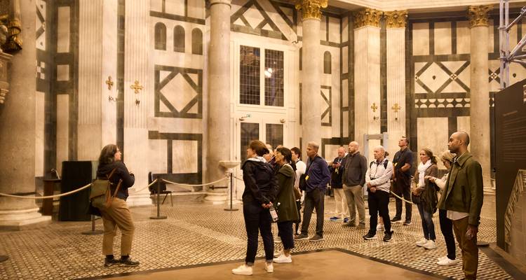 Un guide explique l'art de la Renaissance à un petit groupe de visite à l'intérieur d'une grand hall aux rayures de marbre à Florence.