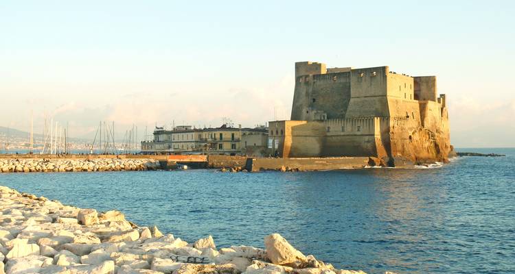 La forteresse en pierre du Castel dell'Ovo qui s'élance dans la mer Tyrrhénienne bleue sous la lumière chaude de la fin d'après-midi.