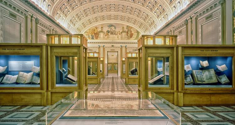 Sala elegante de museo con vitrinas de madera iluminadas y un techo abovedado con frescos.