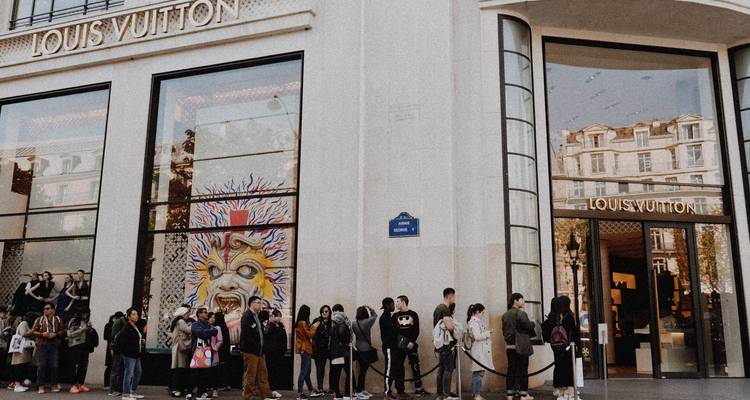File d'attente de clients devant la boutique phare Louis Vuitton sur une rue de la ville.