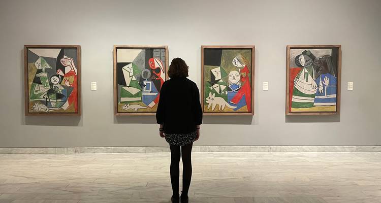 Un visiteur debout seul observant les tableaux de Picasso dans une galerie d'art moderne.