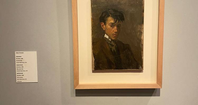 Portrait encadré d'un jeune Picasso exposé sur un mur de galerie gris avec étiquette.