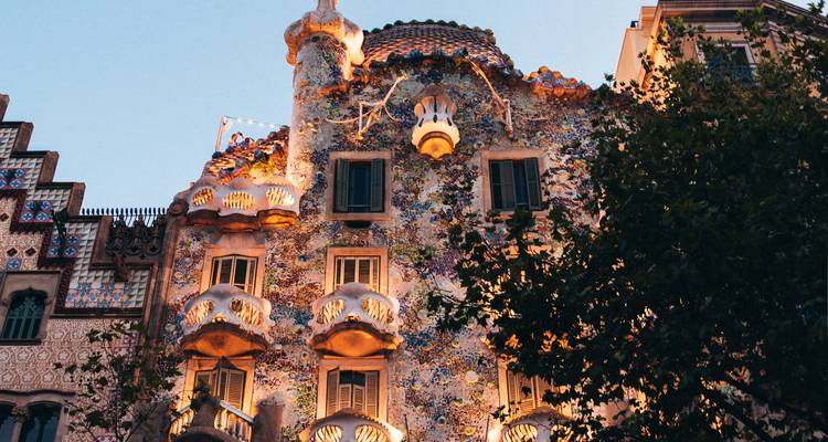 La Casa Batlló illuminée chaleureusement au crépuscule contre un ciel du soir s'assombrissant.