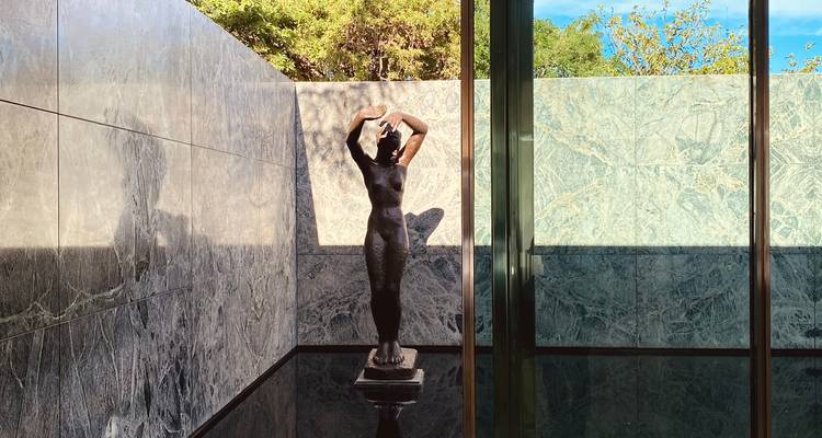 Pavillon en marbre moderniste avec une statue de nu en bronze se reflétant dans une eau immobile.