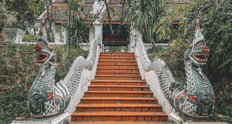Decorative temple staircase guarded by twin naga serpent statues leading up to a pavilion.