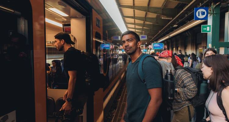 Viajeros con mochilas abordan un tren regional en una estación europea concurrida.