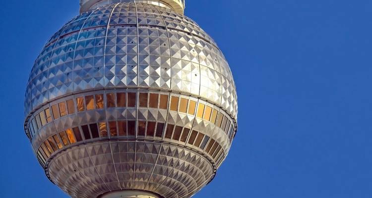 Nahaufnahme des Berliner Fernsehturms vor blauem Himmel.