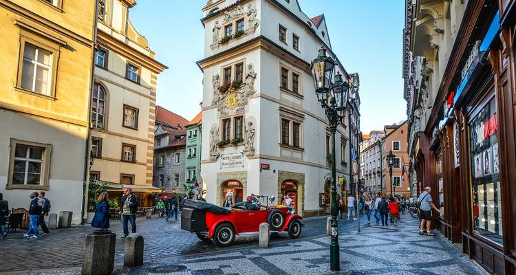 Eine Straße in Prag mit einem roten Oldtimer und historischen Gebäuden.