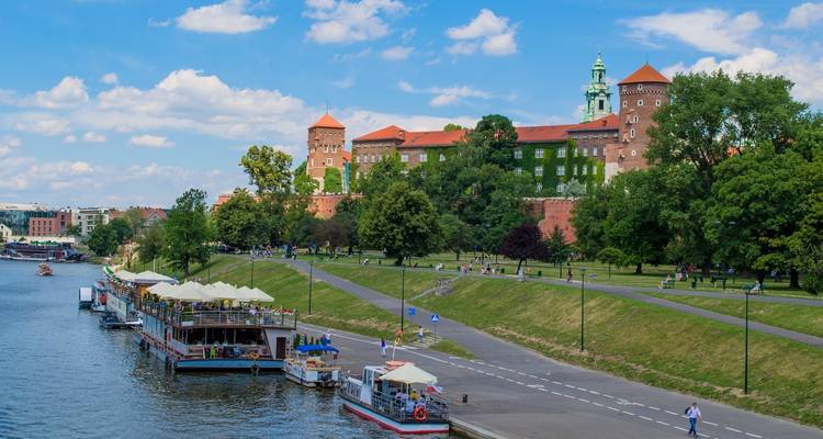 Flussblick auf die Burg Wawel in Krakau mit Booten auf dem Fluss.