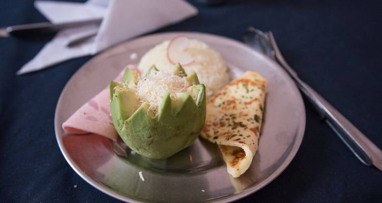Un petit-déjeuner simple dressé comprenant avocat sculpté, riz, jambon et omelette.
