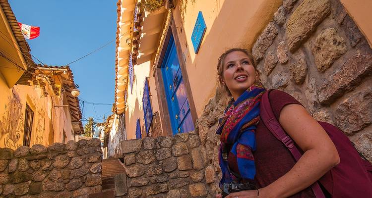 Femme marchant dans une rue historique aux portes bleues.