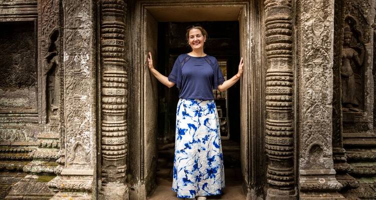Une femme posant à l'intérieur d'un portail de pierre sculptée d'un temple historique.