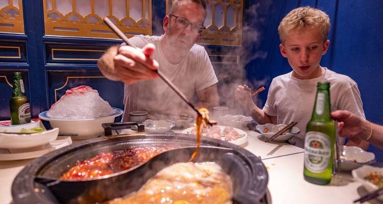 A family enjoying a traditional hot pot meal at a restaurant.