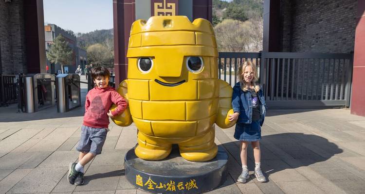 Two children posing with a large, yellow cartoon character statue.