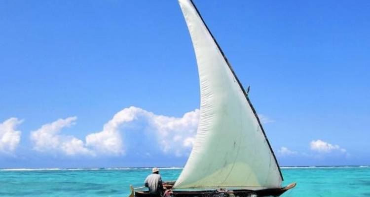 Kleines Segelboot auf türkisfarbenem Wasser mit klarem blauem Himmel.