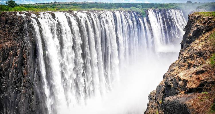 Majestueuze waterval die naar beneden stort in een kloof met oprijzende nevel.